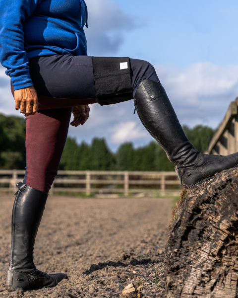 Horse rider wearing Black Equiseat Aid with leg raised on log