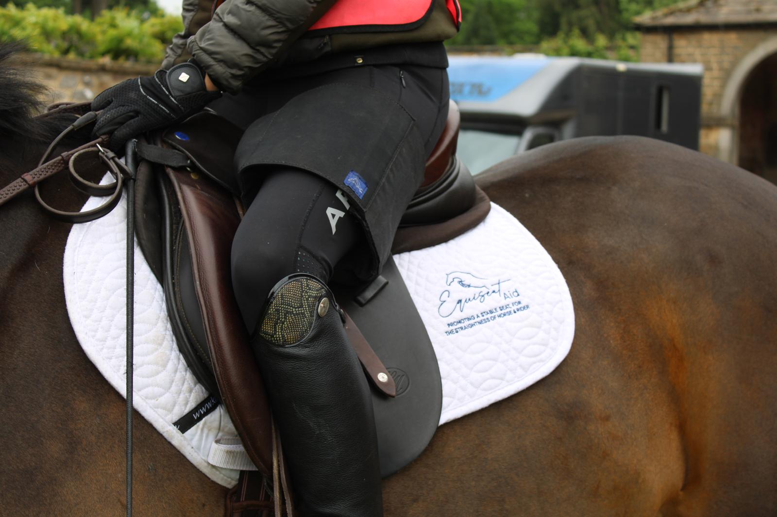 Horse rider wearing black Equiseat Aid, bay horse is wearing an Equiseat aid saddle pad